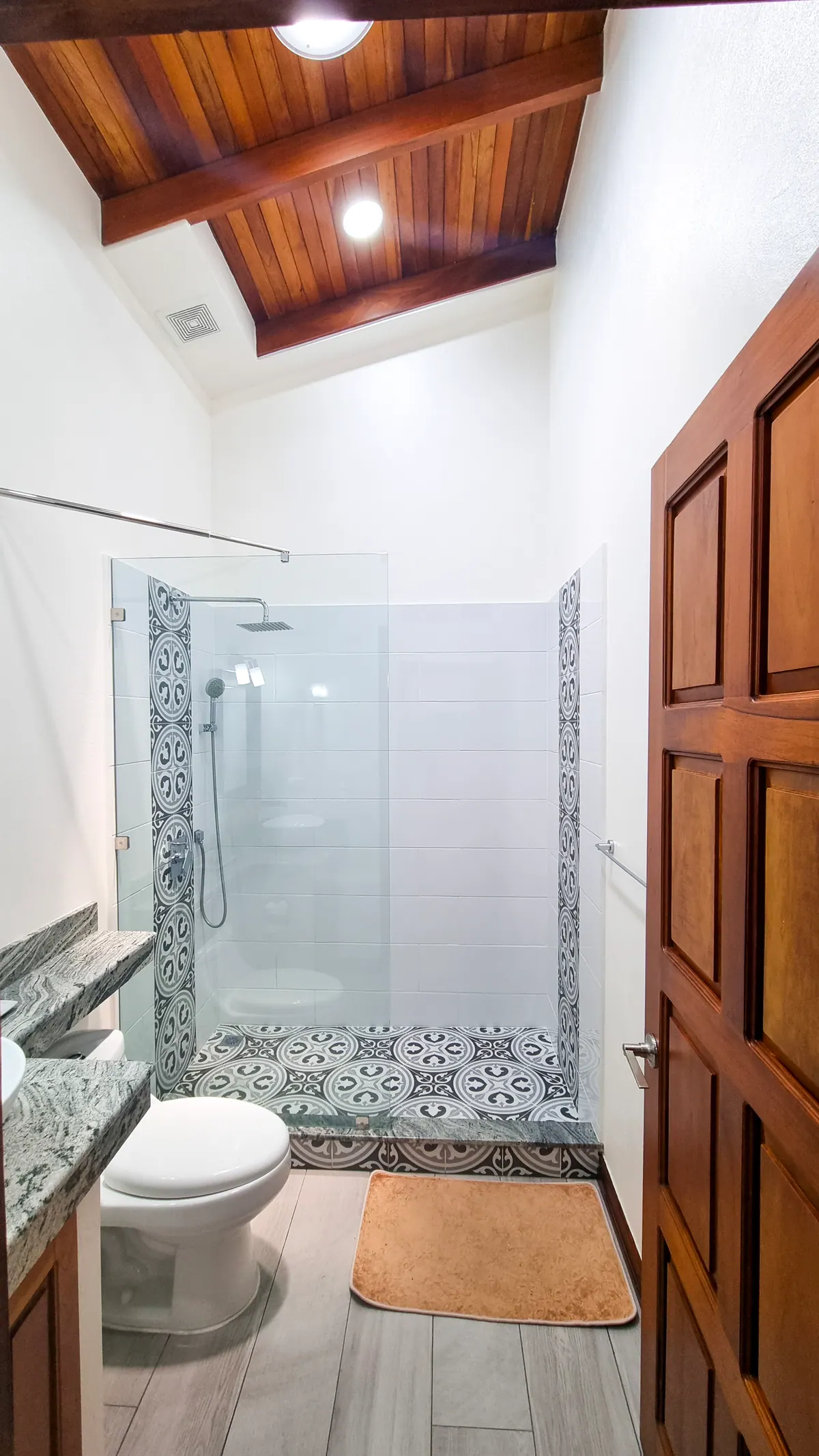 Bathroom with patterned tile walk-in shower and vaulted wood ceiling