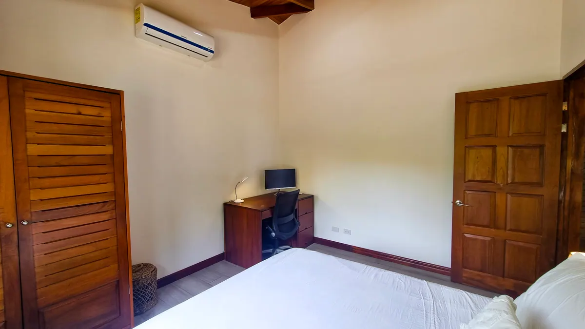 Bedroom corner with desk, external monitor, and air conditioning