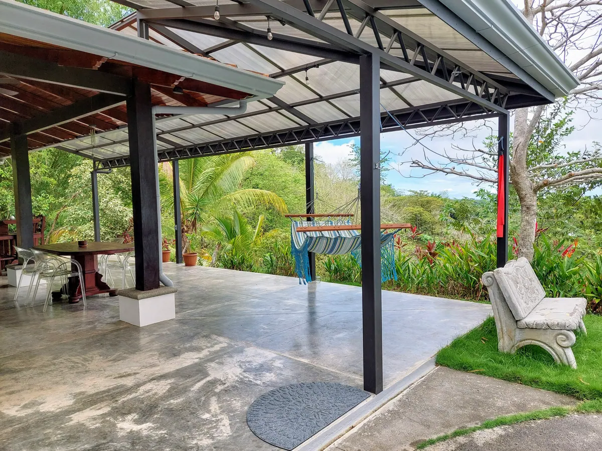 Covered concrete deck with striped hammock and jungle backdrop