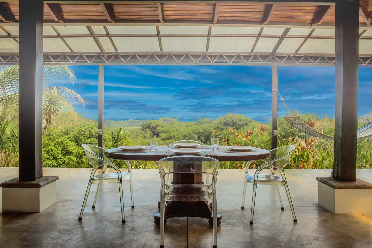 Covered outdoor dining table under a cathedral wood ceiling with valley view