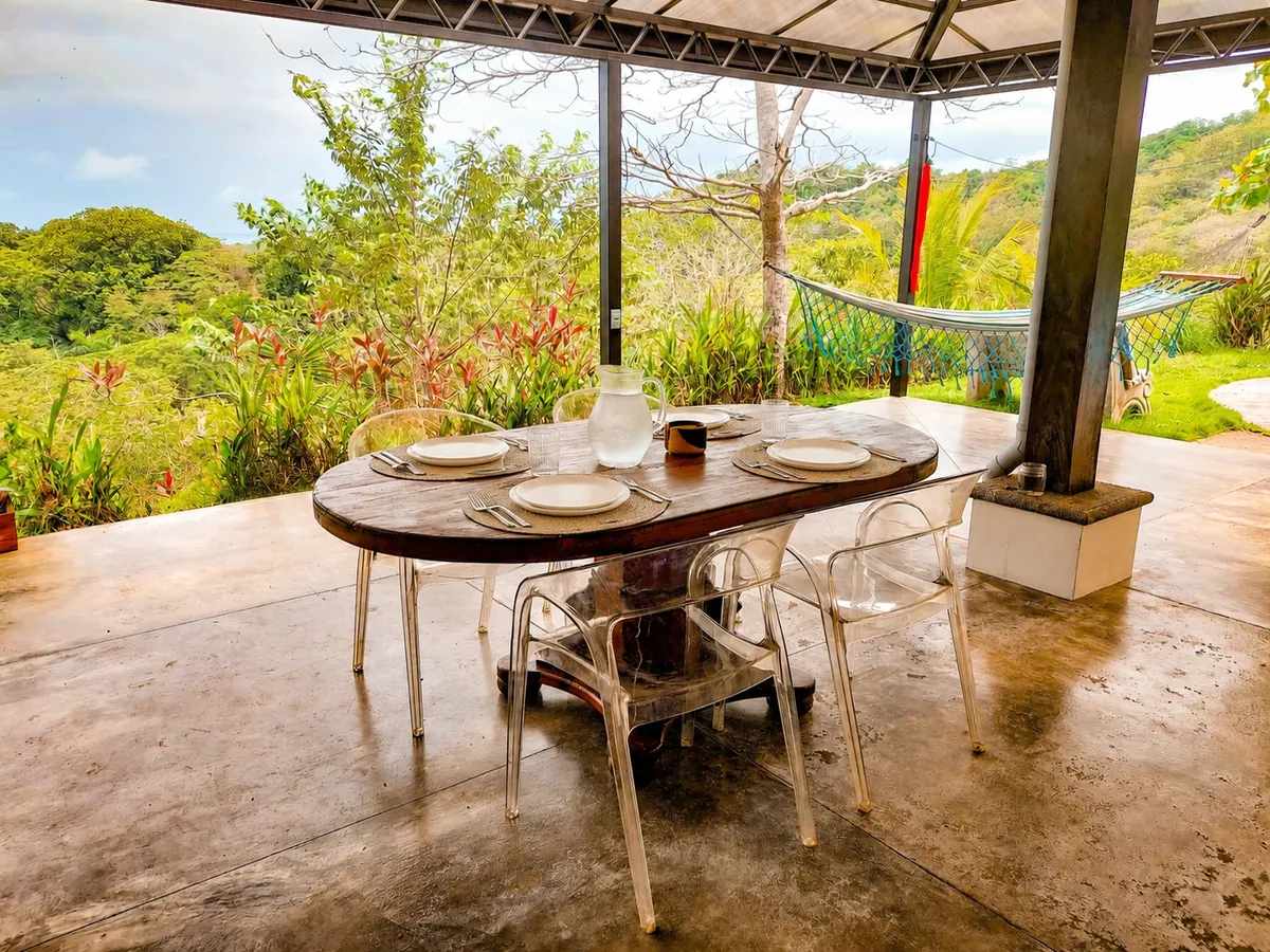 Dining table set for four with hammock and tropical plants in the background