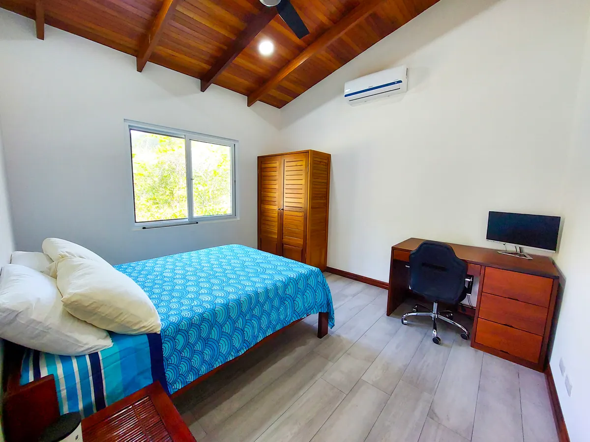 Guest bedroom with desk, monitor, ergonomic chair, and AC