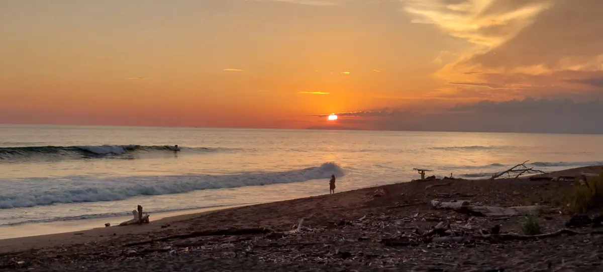 Golden sunset over Playa Hermosa with silhouetted surfer on the shore