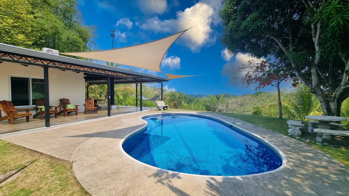 Private pool with shade sail, deck chairs, and jungle view at Villa Hermosa