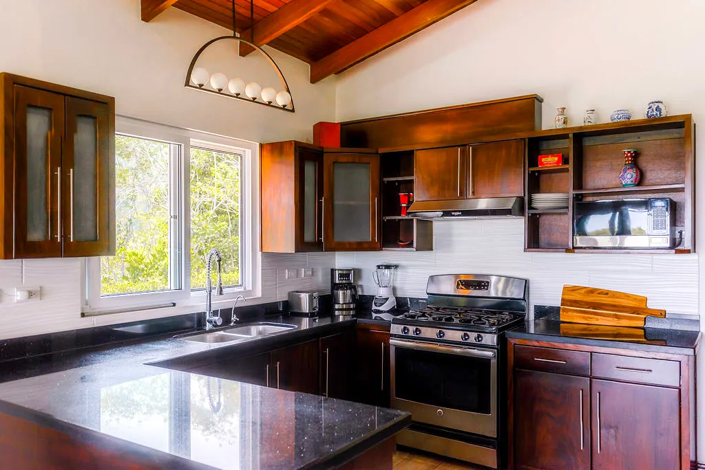 Modern kitchen with dark hardwood cabinets, gas stove, and granite counters