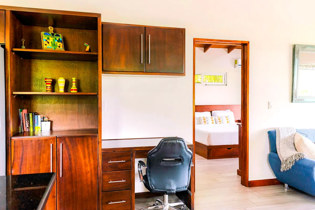 Built-in hardwood desk and bookshelf with ergonomic chair facing the bedroom